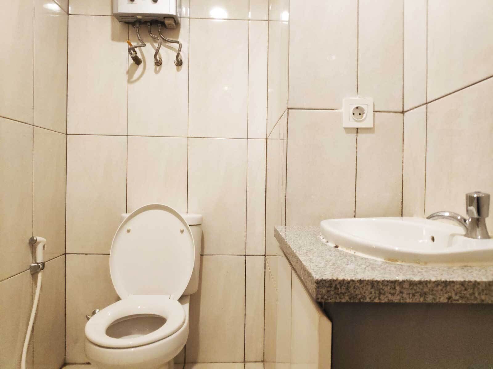 Une salle de bain équipée de toilettes, d’un lavabo et d’une prise électrique murale.