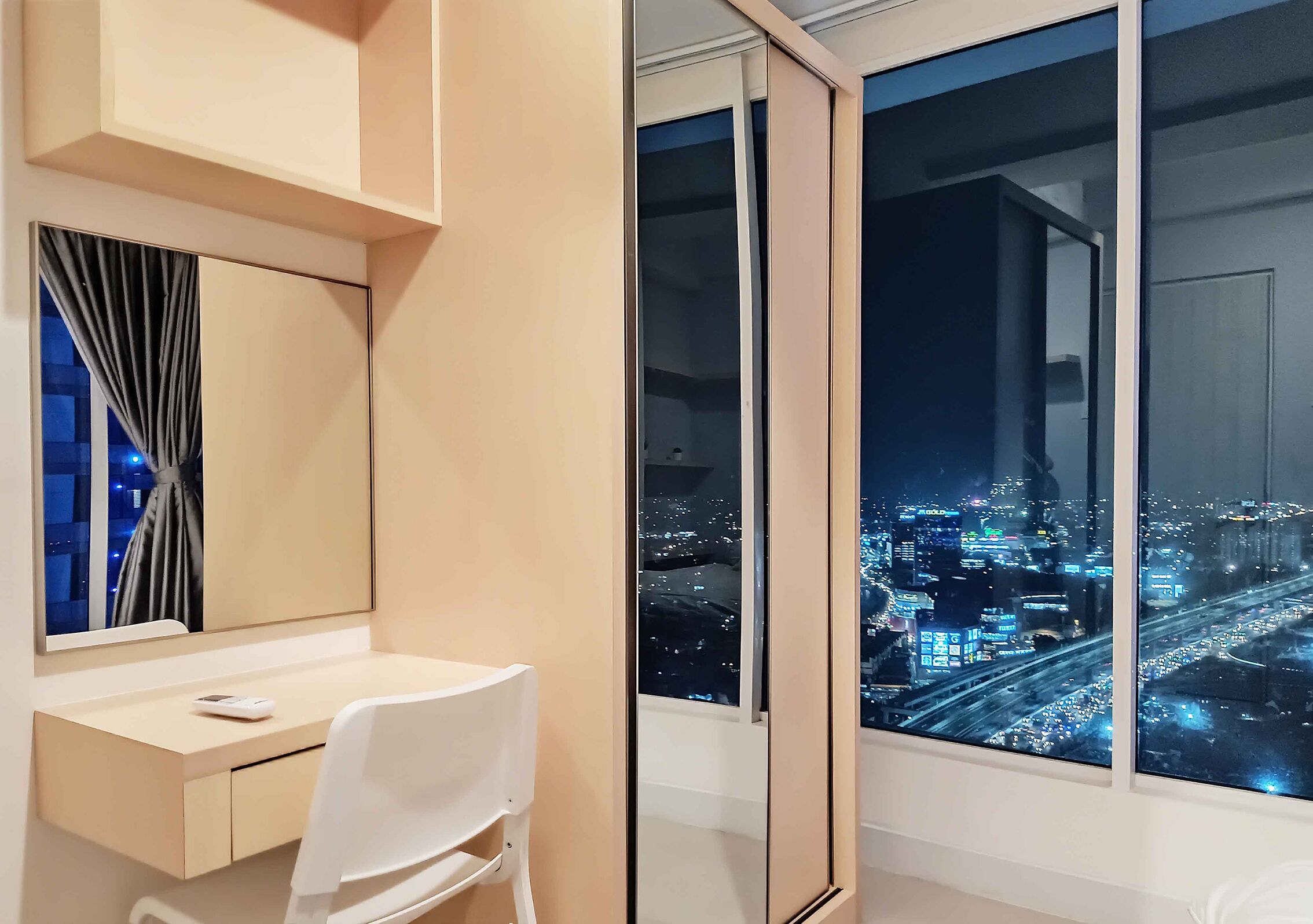 A modern hotel room with a large window offering a nighttime city view.