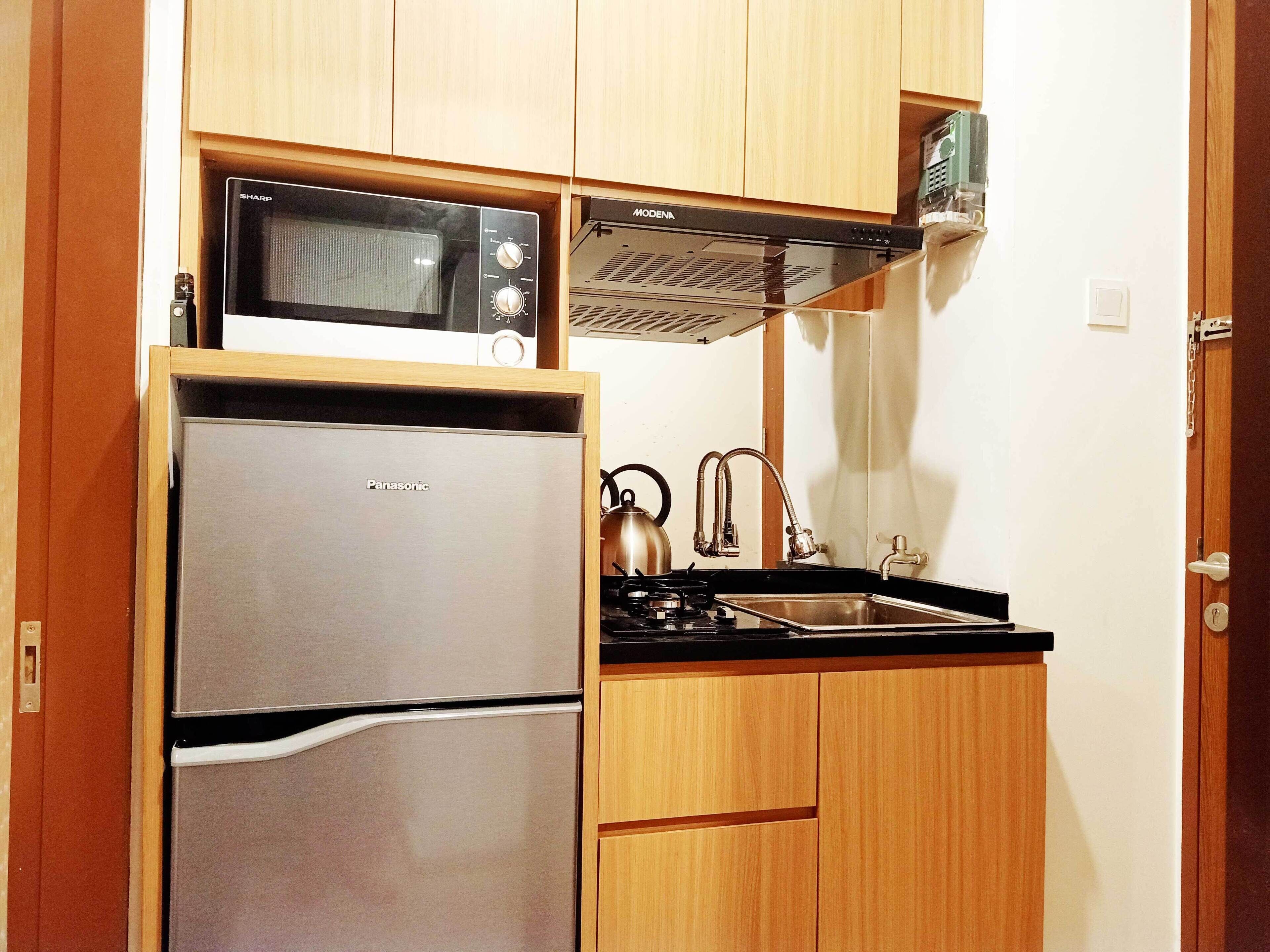 A compact kitchen with a stainless steel refrigerator, a microwave, and a stove.