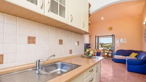 Una cocina con lavamanos, armarios y una zona comedor con mesa y sillas.