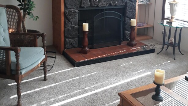 Ein gemütliches Wohnzimmer mit Kamin, einem darüber hängenden Gemälde, einem hölzernen Sims und einem Blumentopf.