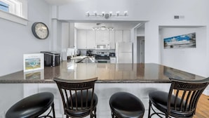 A modern kitchen with white cabinets, a central island, and a dining area with three chairs.