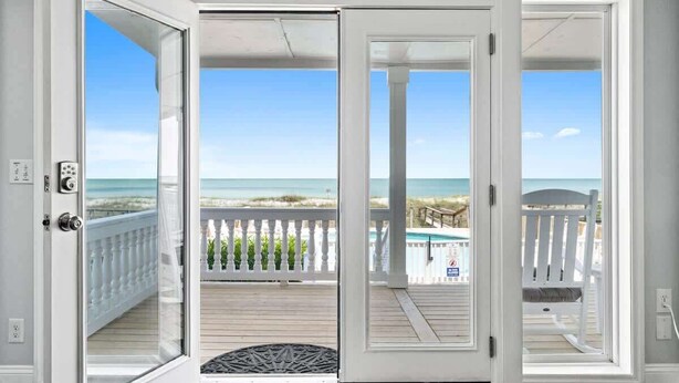 A room with a sliding glass door leading to a balcony with a view of the beach and ocean. - Sea2Sky by Carolina Getaway - Oceanfront Home w/ Private Pool & Heated Spa (Kure Beach)