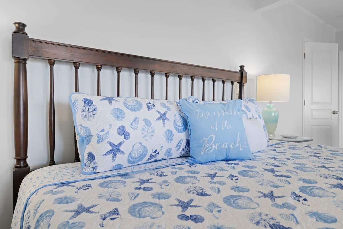 A bed with a blue and white patterned bedspread, two pillows with similar designs, and a wooden headboard.