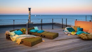Une terrasse avec des sièges extérieurs, un phare et une vue sur la mer.