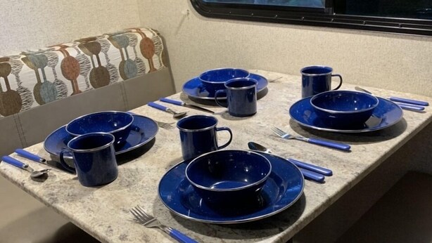 Un coin repas avec une table dressée pour quatre personnes, agrémentée d’assiettes et de tasses bleues.