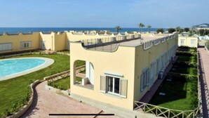 Un complexe hôtelier doté d’une piscine, d’une pelouse bien entretenue et offrant une vue sur la mer.