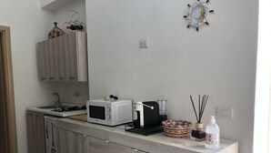 Une cuisine moderne équipée d’un four à micro-ondes encastré, d’une machine à café et d’un petit évier.