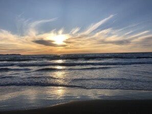Een strand met golven en een zonsondergang.