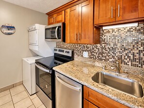 A kitchen with wooden cabinets, a microwave, a stove, a dishwasher, and a tiled backsplash.