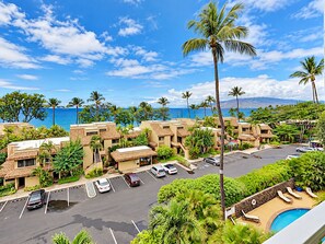 A resort with multiple buildings, a parking lot, and a pool area with lounge chairs.