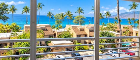A balcony with a view of a beach and ocean, featuring a table and chairs.