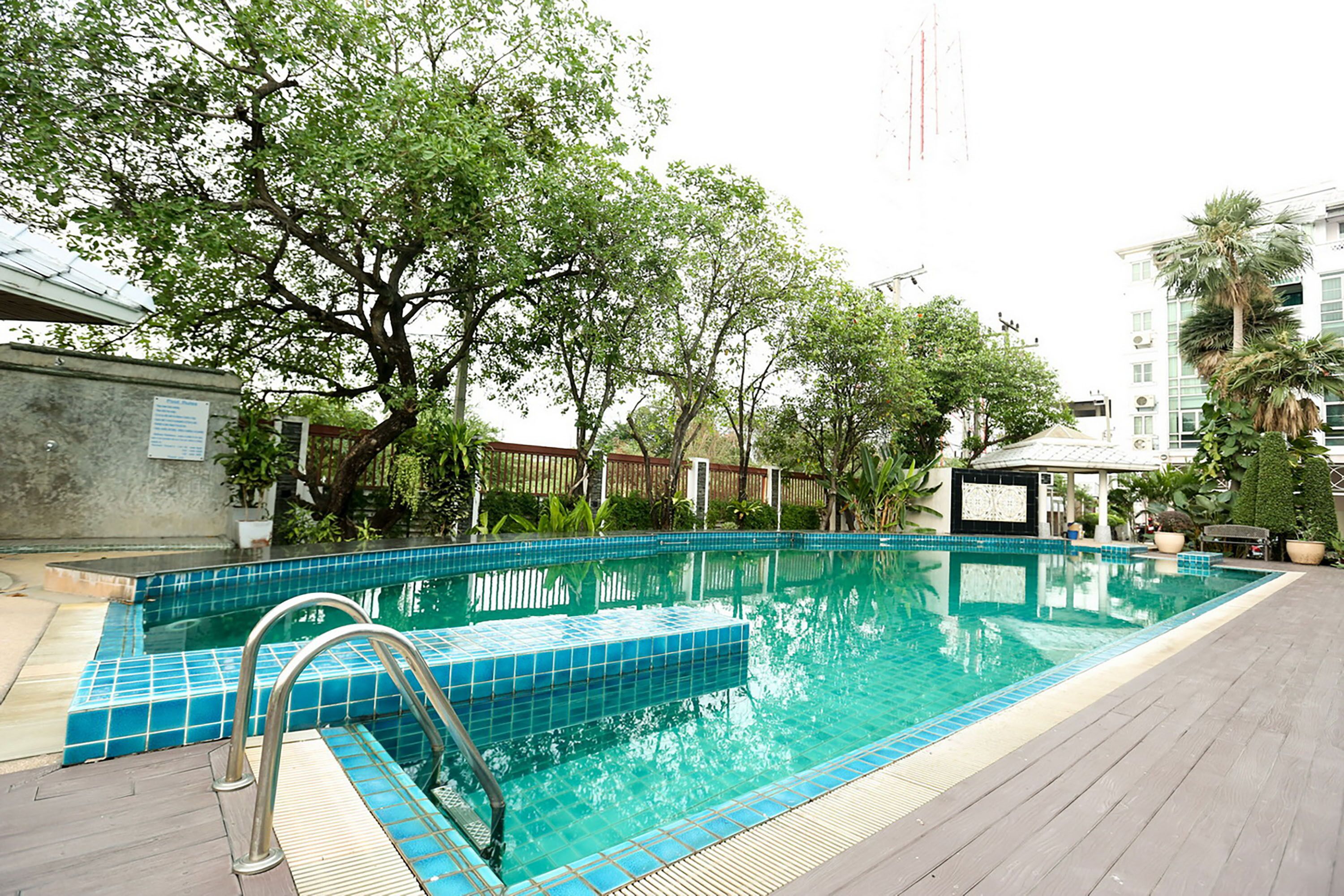 A swimming pool with a tiled edge, surrounded by trees and a wooden deck.