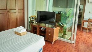 A hotel room with a bed, a television on a wooden stand, a wardrobe, and a sliding glass door leading to a bathroom. - Bellevue Boutique Bangkok (Bangkok)