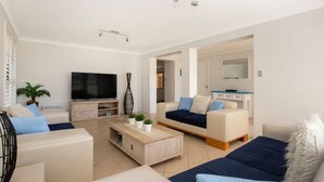 Una sala de estar moderna con una televisión de pantalla plana, dos sofás, una mesa de centro y un mueble para televisión.