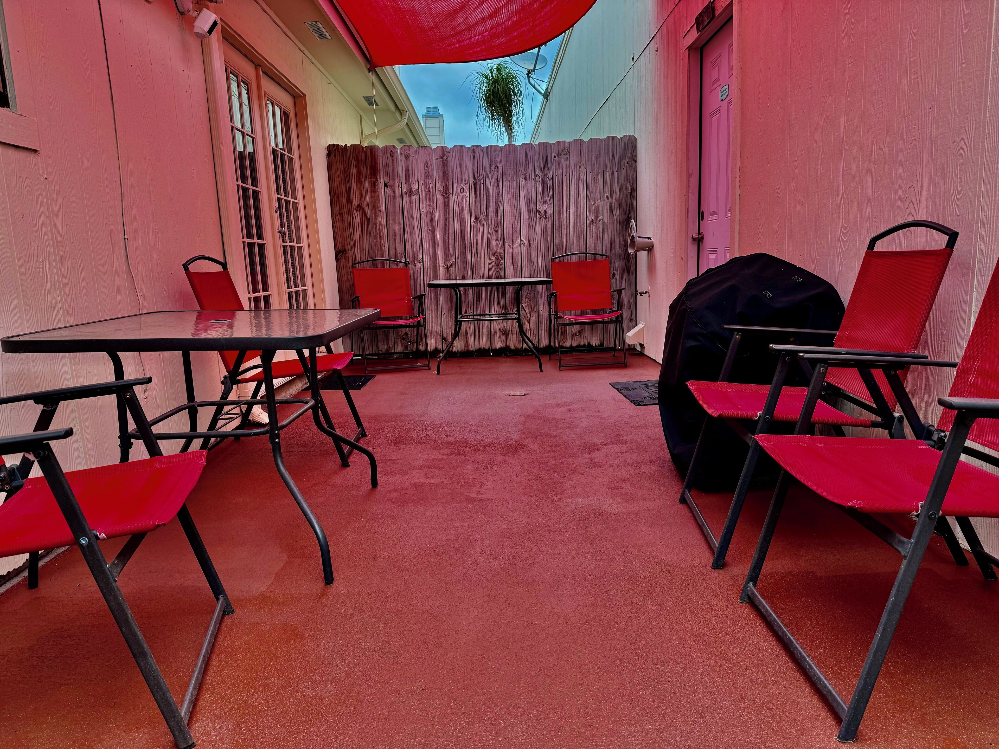 Un espace extérieur aménagé avec des chaises rouges, une table et un barbecue.