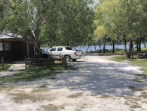 A white pickup truck parked near a wooden structure by a lake. - The Lake Store Lodging Room #2 (Winnsboro)