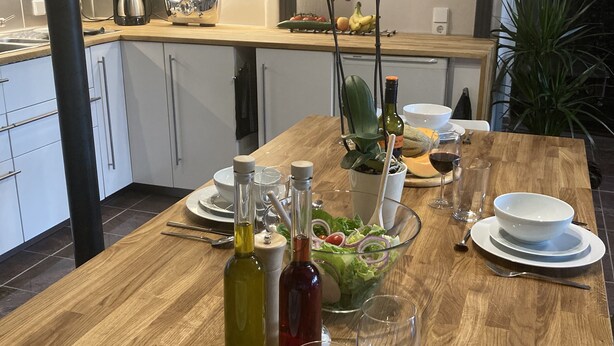 A dining table set with plates, bowls, cutlery, and bottles of olive oil. - Ferienidylle Haus Königsberg, Child-friendly, Dog-friendly, Barrier-free (Michelstadt)