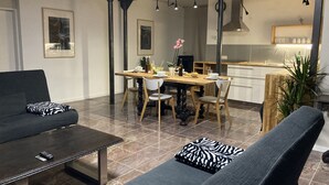 A modern living room with a sofa, a dining table, and a kitchen area. - Ferienidylle Haus Königsberg, Child-friendly, Dog-friendly, Barrier-free (Michelstadt)