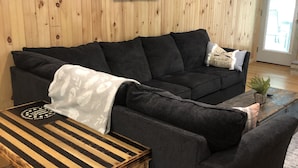 A living room with a dark grey sectional sofa, a wooden coffee table, and a framed picture on the wall. - Welcome to Mountain Momma (Mount nebo)
