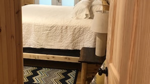 A wooden-paneled room with a bed, a nightstand, and a wall-mounted sign. - Welcome to Mountain Momma (Mount nebo)