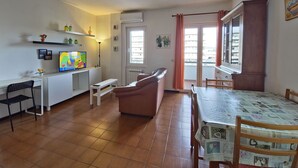 Een compacte leefruimte met een kitchenette, een eethoek en een zithoek met een bank en een tafel.