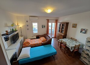 Una habitación compacta con dos camas, un escritorio, una silla, una mesa de comedor y un armario.