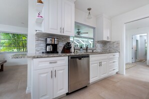 Une cuisine moderne avec des meubles blancs, un plan de travail en granit et un lave-vaisselle.