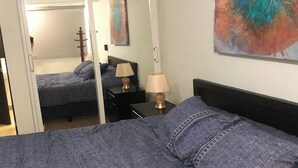 Une chambre à coucher avec un lit, des tables de chevet, une lampe et un tableau au mur.