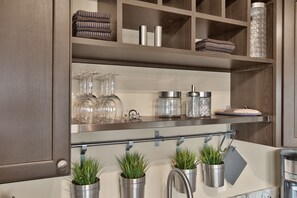 Una cocina con armarios de madera, protector contra salpicaduras de acero inoxidable y tres macetas.