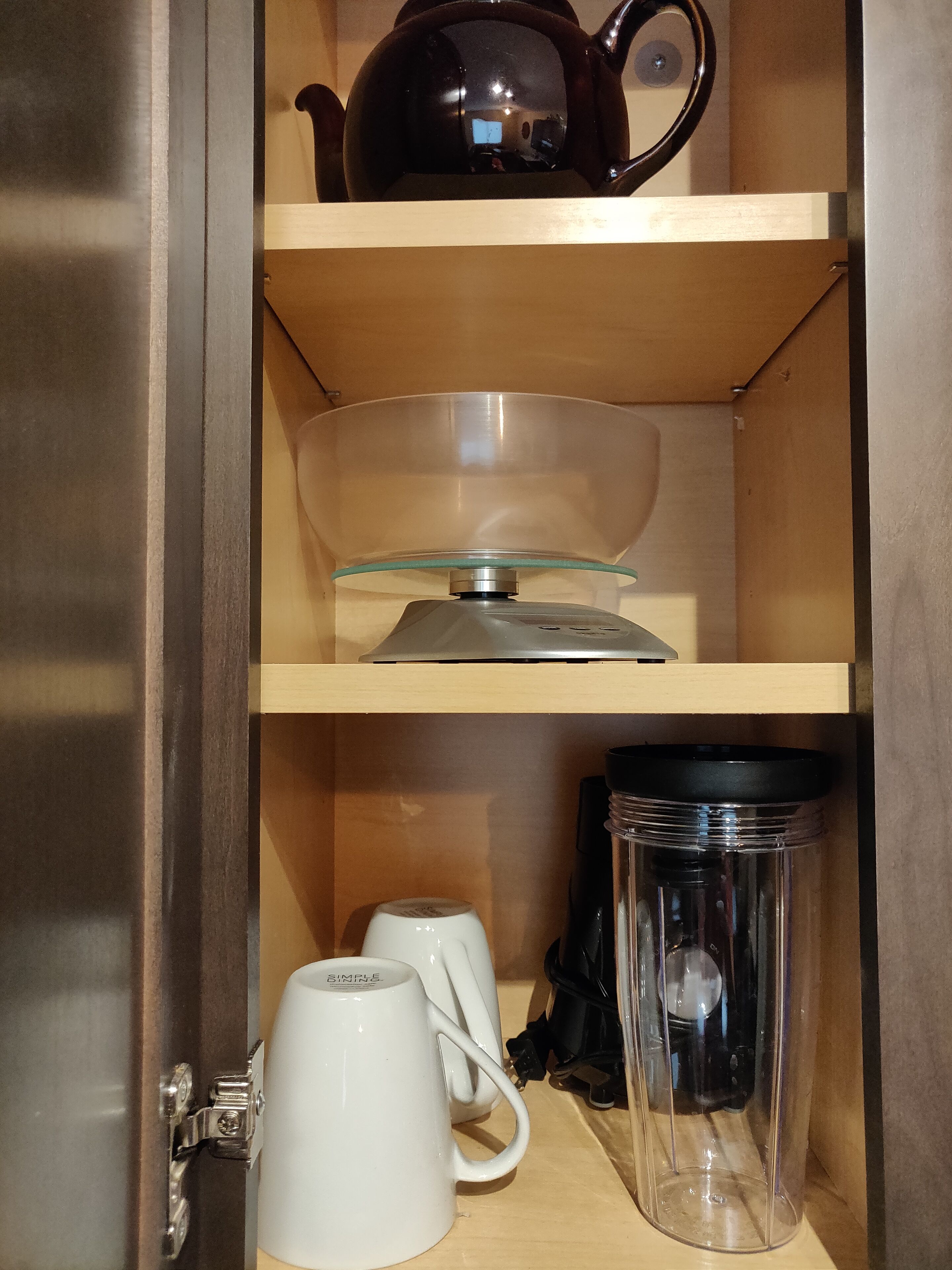 Una estantería de madera con un hervidor, un bol de vidrio, una cafetera y una botella de agua.