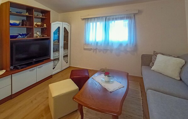 Un espacio habitable compacto con televisor, mueble de madera y comedor con mesa y sillas.