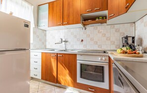 A compact kitchen with wooden cabinets, a built-in oven, a sink, and a coffee maker.