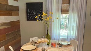A dining area with a wooden wall, a blackboard with a quote, a table set with plates, glasses, and a vase with yellow flowers.