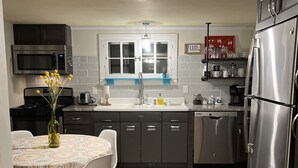 A modern kitchen with dark cabinets, a stainless steel refrigerator, a microwave, and a dishwasher.