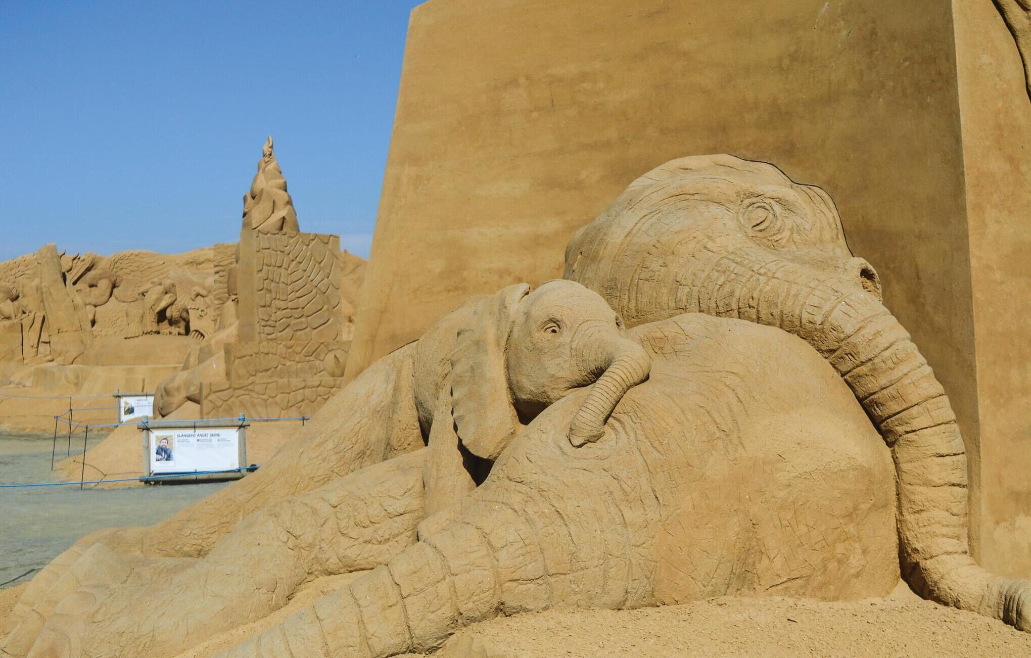 Una gran escultura de arena con un elefante y una jirafa.