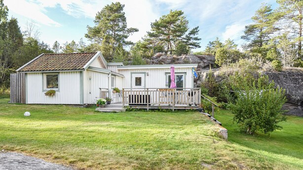 A white mobile home with a porch, surrounded by a grassy yard and trees. - Lovely home in Strömstad with WiFi (Strömstad)