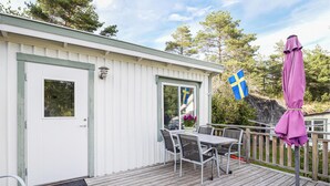 A white building with a door and windows, a deck with chairs and a table, and a Swedish flag. - Lovely home in Strömstad with WiFi (Strömstad)