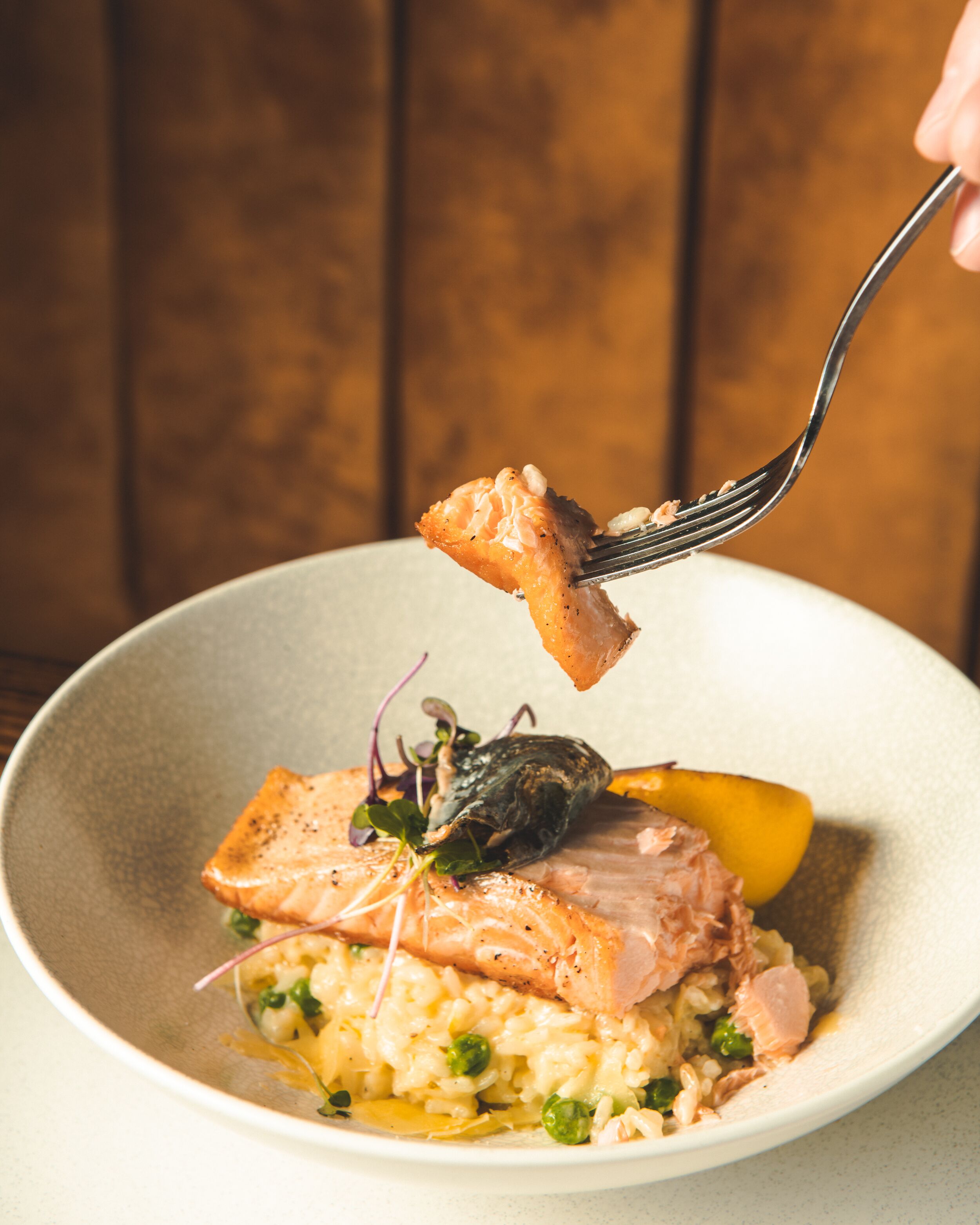 A plate of food with salmon, peas, and a lemon slice.