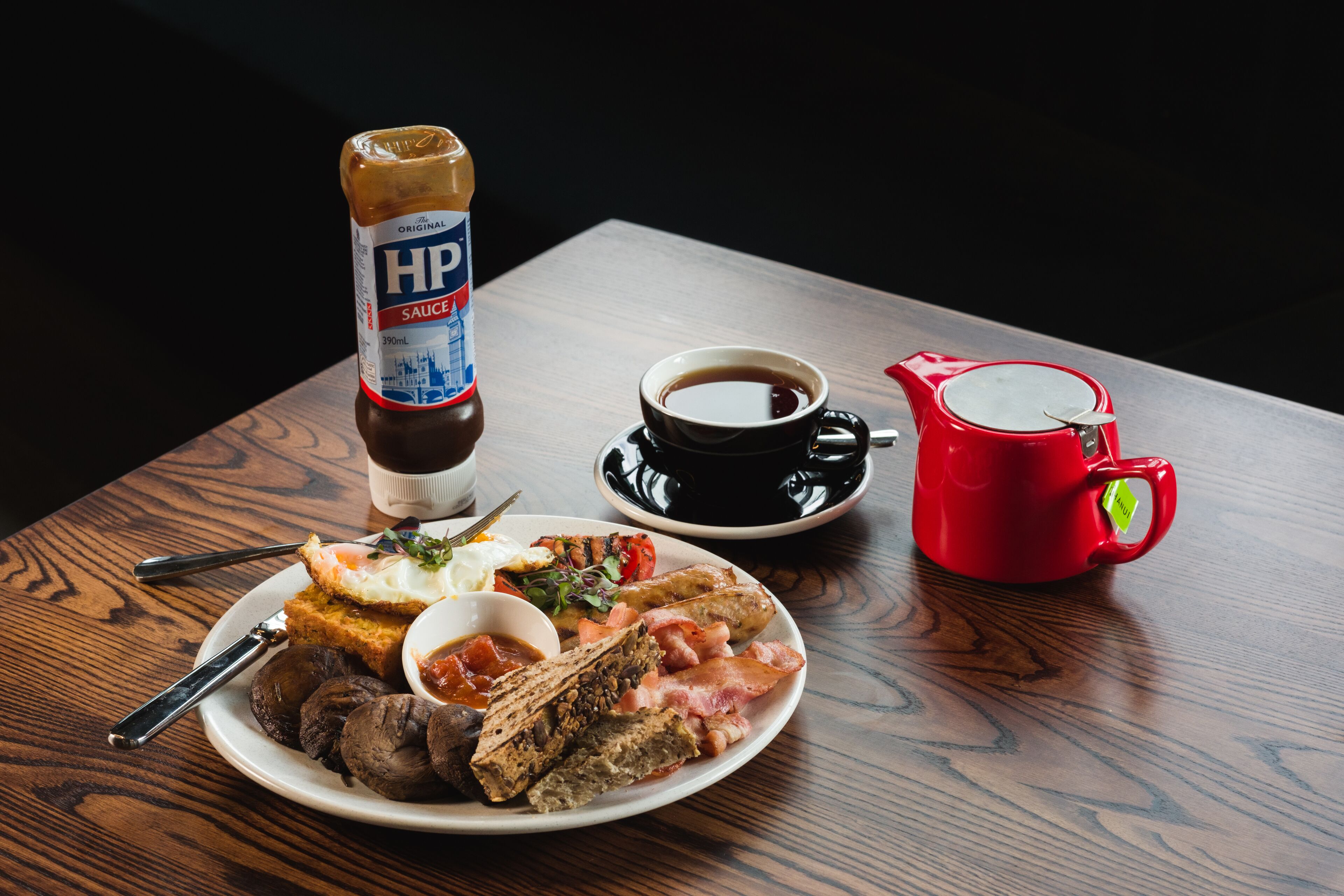 A breakfast plate with eggs, bacon, toast, and a bottle of HP sauce.
