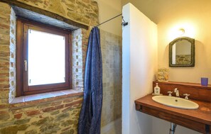 A bathroom with a stone wall, a wooden window, a shower curtain, a sink with a mirror, and a soap dispenser. - Lovely apartment in San Vito in Monte with house a panoramic view (San Vito in Monte)