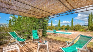 Ein überdachter Außenbereich mit Liegestühlen und einem Pool.