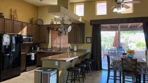 Una cocina moderna con una isla central, taburetes de bar y un comedor con mesa y sillas.