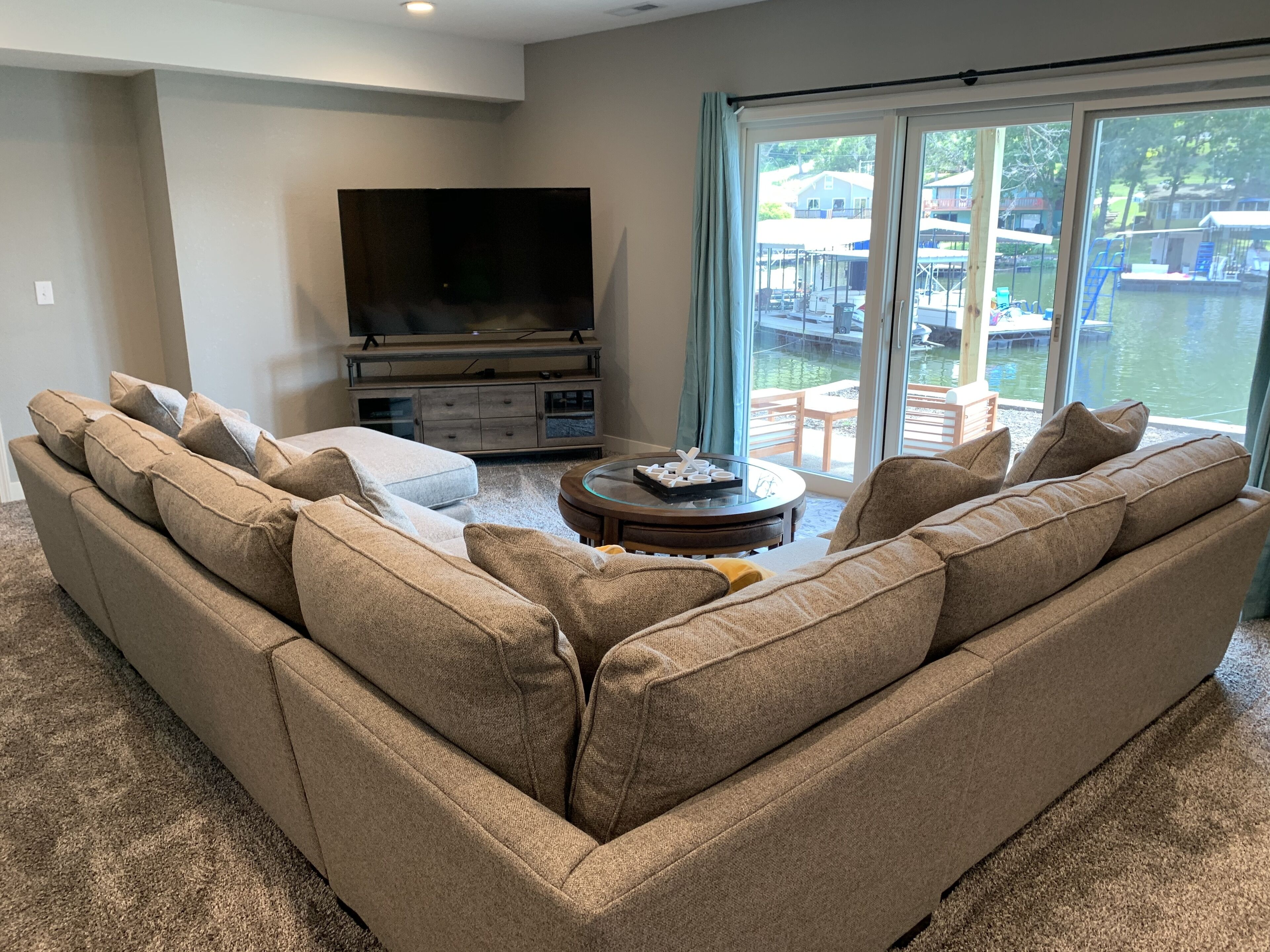 A living room with a beige sectional sofa, a flat-screen TV, and a glass coffee table.