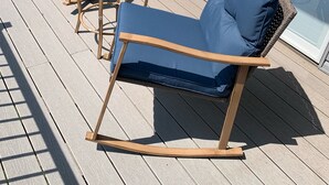 A deck with two blue cushioned chairs and a small round table. - Completely renovated home in Quiet Cove with a Dock! (Sunrise Beach)