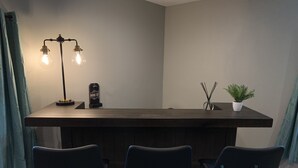 A bar area with a dark wooden counter, three black chairs, a black lamp, a small potted plant, and a decorative item on the counter. - Completely renovated home in Quiet Cove with a Dock! (Sunrise Beach)
