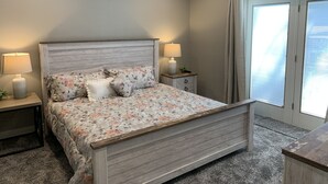 A bedroom with a bed, two bedside tables with lamps, a ceiling fan, and a window with blinds. - Completely renovated home in Quiet Cove with a Dock! (Sunrise Beach)