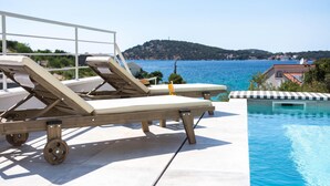 Un espace aménagé au bord de la piscine, avec deux chaises longues et une piscine.