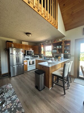 Une cuisine moderne avec des meubles en bois, des appareils en acier inoxydable et un îlot central doté de tabourets de bar.