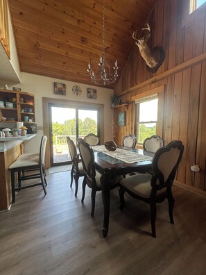 Un coin repas avec une table en bois, des chaises et un lustre.